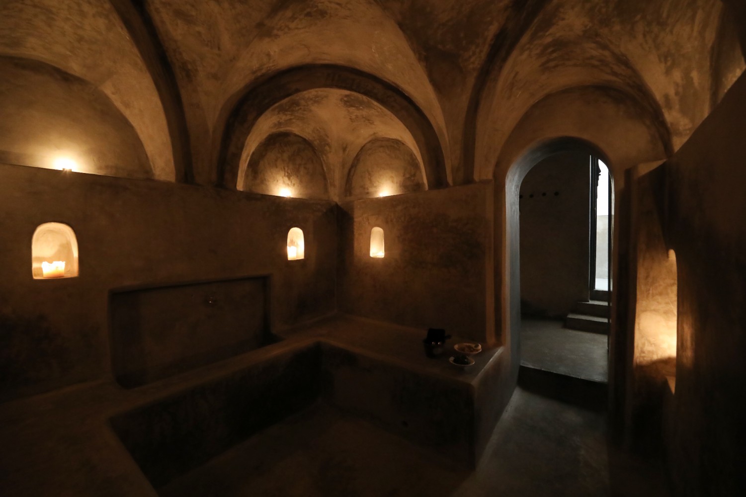 The black tadelakt vaults of the hammam, candles lit in the niches