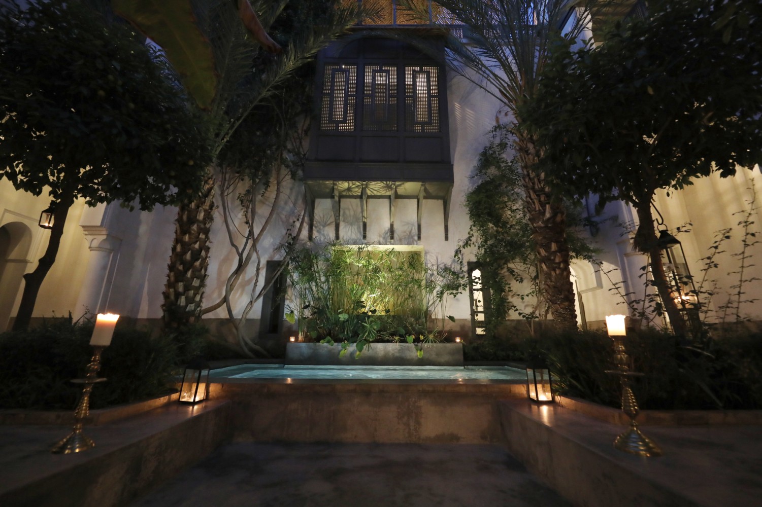The patio pool at night, ringed with candles and brass candlesticks